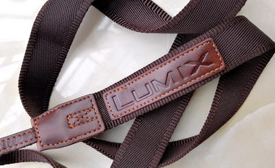 一个松下LX系列相机用的栗棕色帆布背带（上面一侧有英文LUMIX字